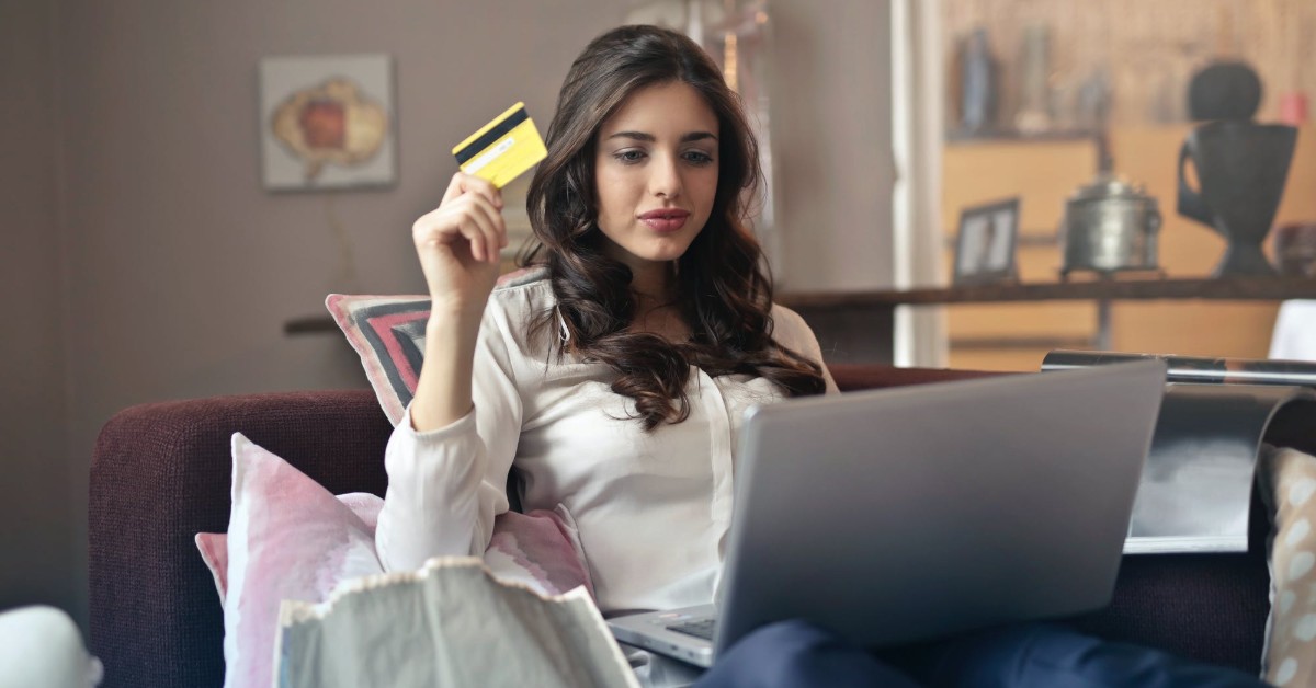 girl holding credit card on laptop in living room