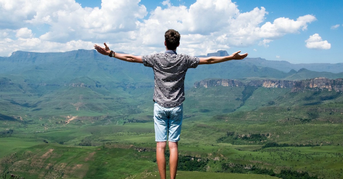 man standing on a mountain top with him arms wide open